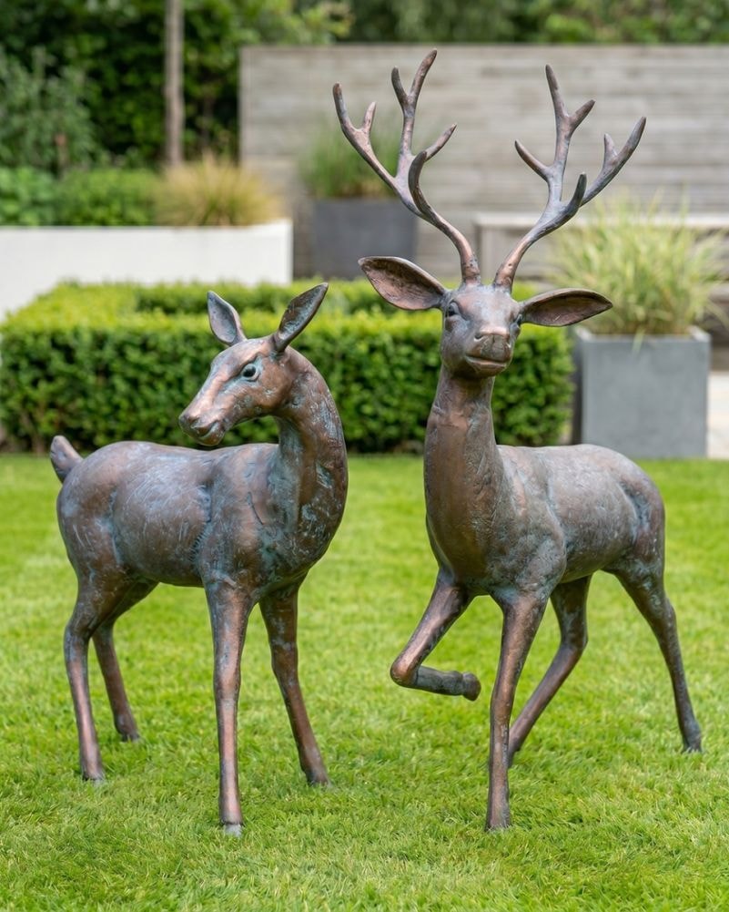 Cast aluminium stag and doe sculptures standing on a garden lawn